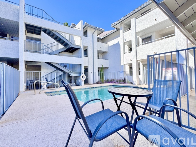 A poolside table and chairs are set up in front of a white apartment building.