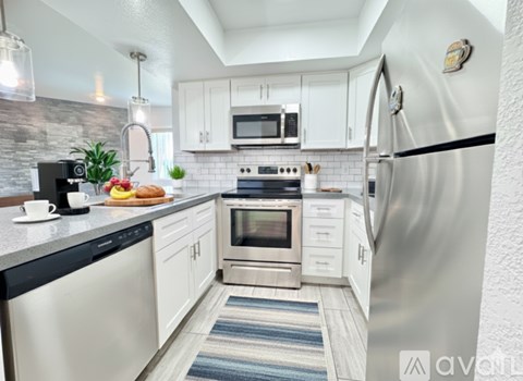 A kitchen with white cabinets and a stainless steel refrigerator.