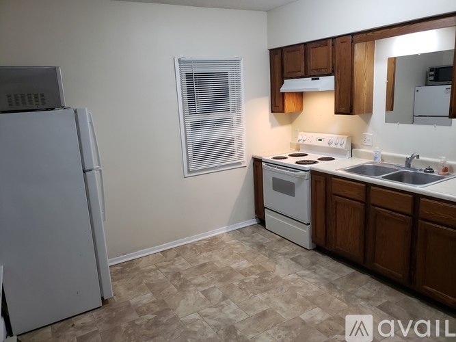 A kitchen with a white refrigerator, wooden cabinets, and a tiled floor.