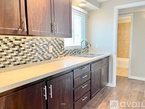 A kitchen with dark wood cabinets and a checkered backsplash.