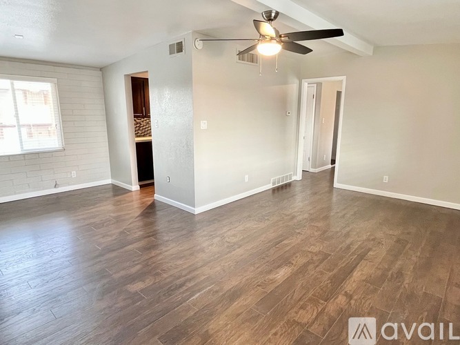 A spacious room with wood flooring and a ceiling fan.