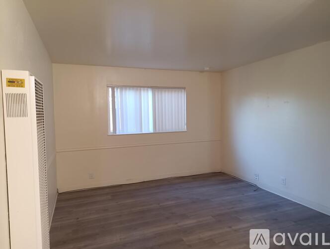 A room with wooden flooring and a window with blinds.