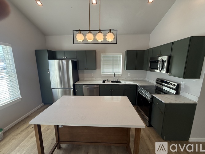 A kitchen with a white table and dark green cabinets.