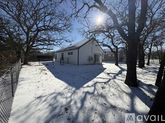 A house with a fence and trees around it in the snow.