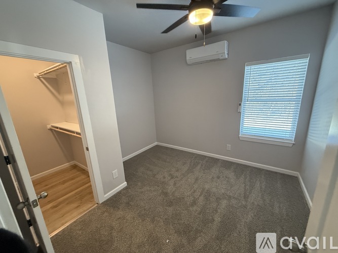 A room with a ceiling fan and a window with blinds.
