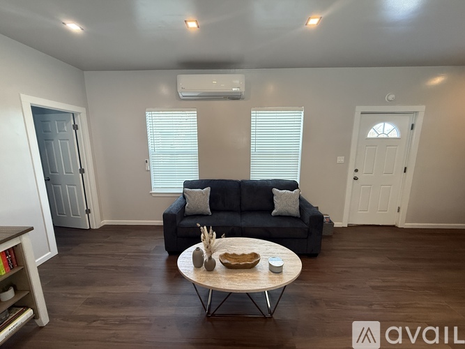 A living room with a black couch, a wooden coffee table, and a bookshelf.