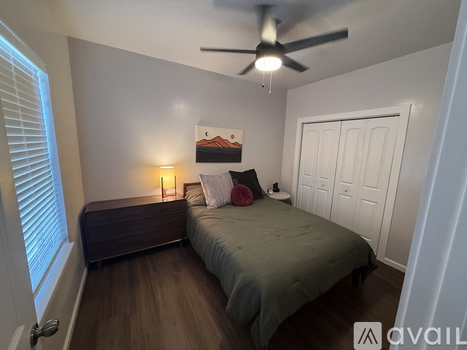 A bedroom with a bed, a bench, and a ceiling fan.
