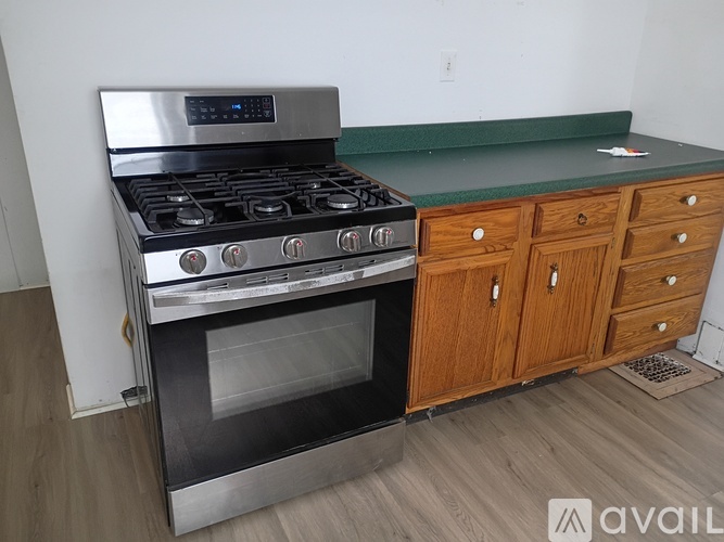 A modern kitchen with a stainless steel gas stove and wooden cabinets.