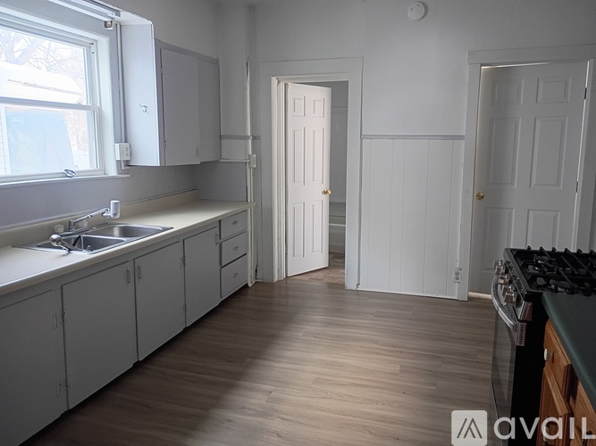 A kitchen with white cabinets and a wooden floor.