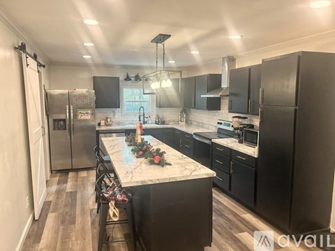 A kitchen with black cabinets and a marble island.