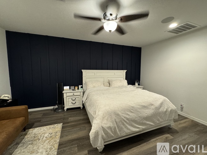 A bedroom with a white bed and a ceiling fan.