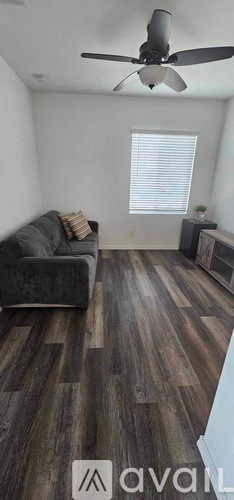 A living room with a grey couch and a ceiling fan.