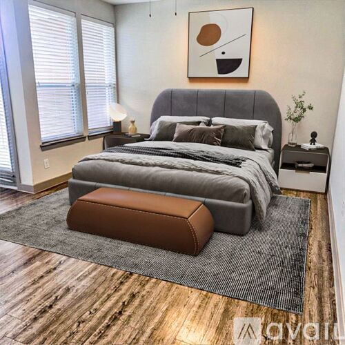 A bedroom with a large bed and a brown ottoman.