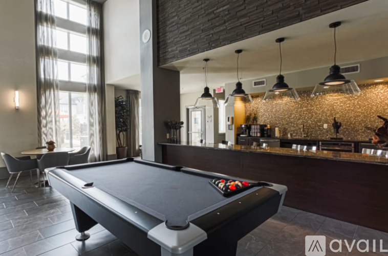 A pool table is in the middle of a room with a bar and a dining table.
