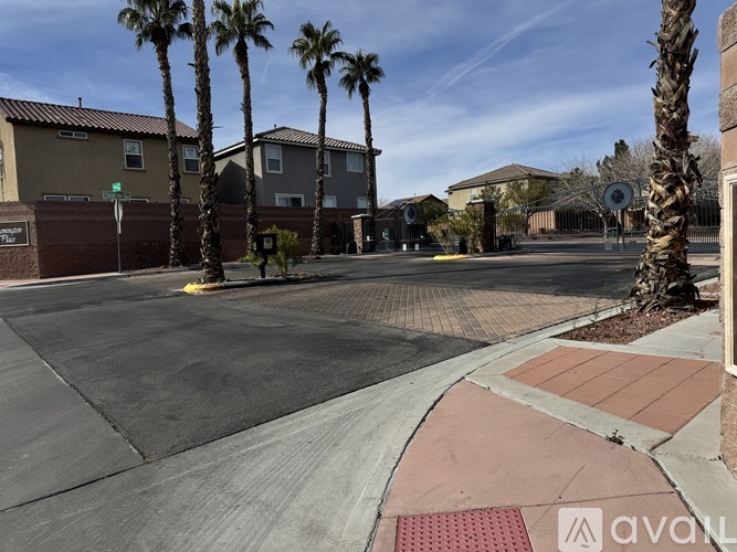 A street view of a residential area with palm trees and houses.
