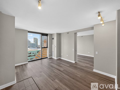 A spacious room with wooden flooring and a large window overlooking a cityscape.
