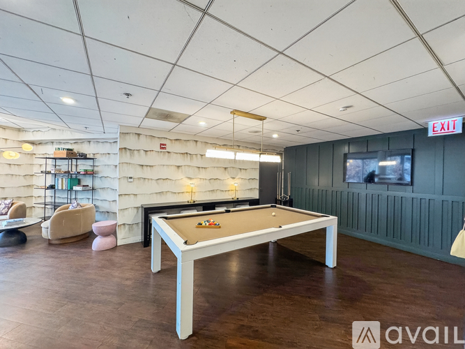 A pool table is in the middle of a room with a white ceiling and a TV on the wall.