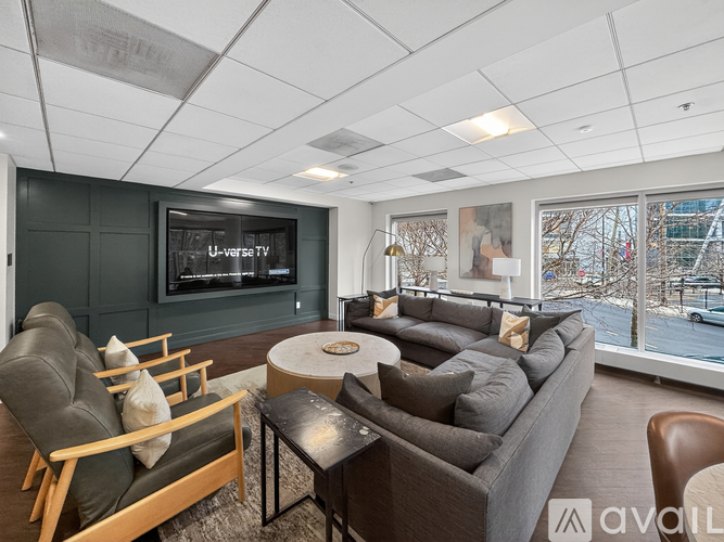 A living room with a grey couch and a flat screen TV mounted on the wall.