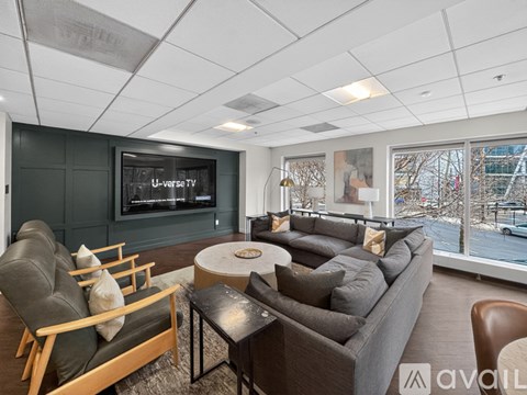 A living room with a grey couch and a flat screen TV mounted on the wall.