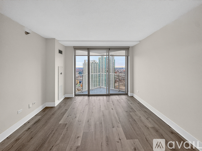 A spacious room with wooden flooring and a view of the city through a large window.