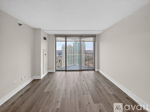A spacious room with wooden flooring and a view of the city through a large window.