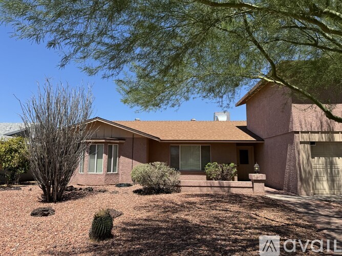 A house with a brown roof and a brown fence with a tree in front.