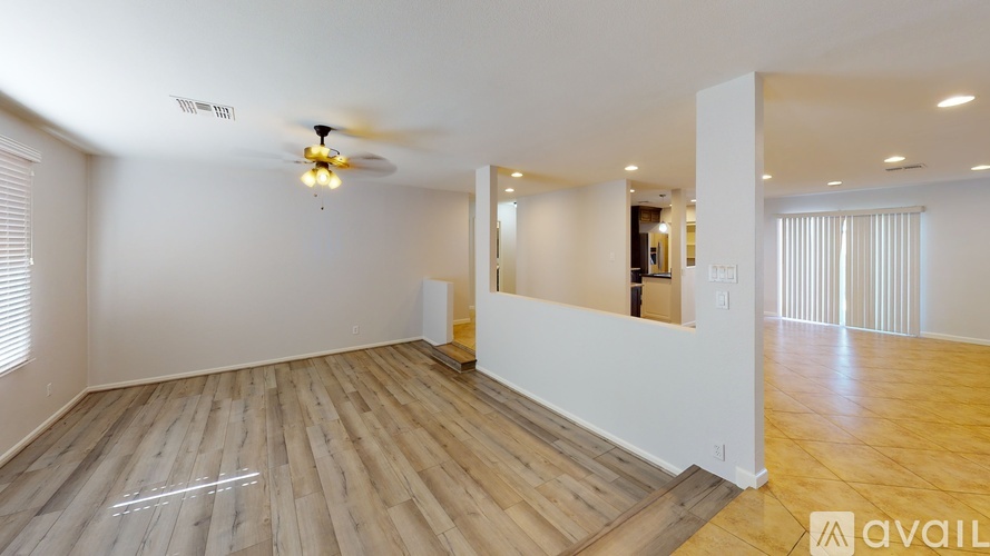 A spacious room with wooden flooring and a ceiling fan.