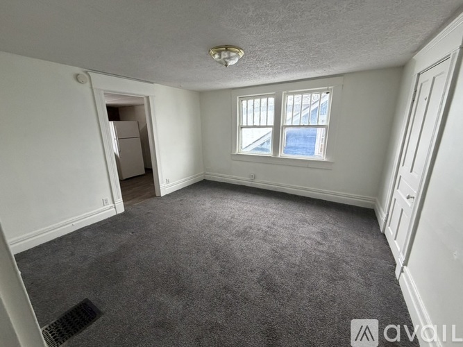 A room with a carpeted floor, a window, and a door.