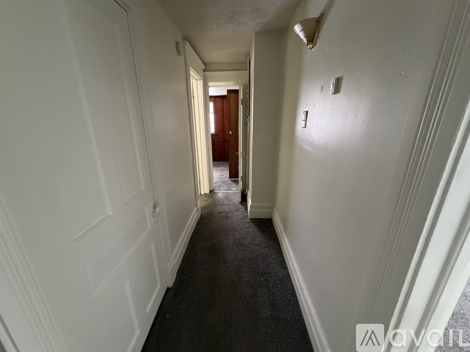 A long hallway with white walls and a black carpet.