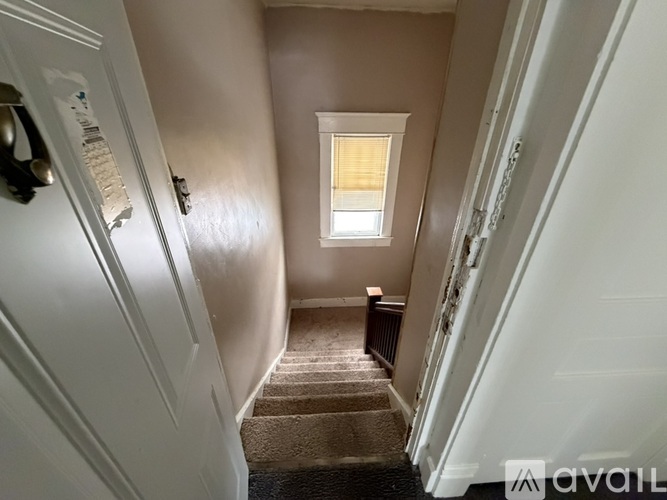 A stairway with a carpeted runner and a small window at the top.