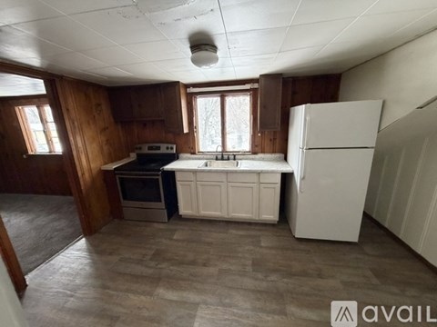 A kitchen with wooden walls and a white refrigerator.
