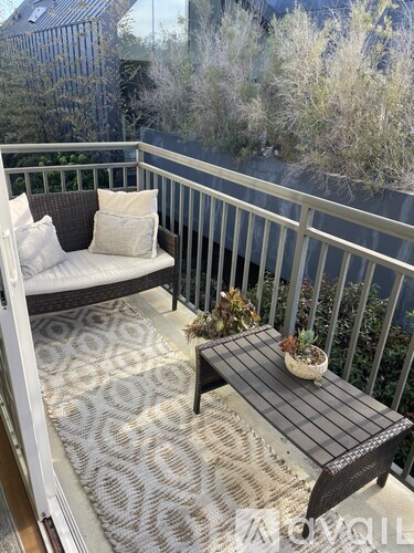 A balcony with a white couch, a black table, and a potted plant.
