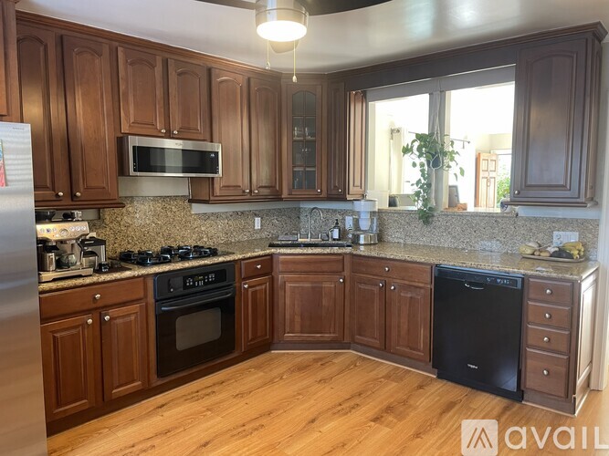 A kitchen with wooden cabinets and a black dishwasher.