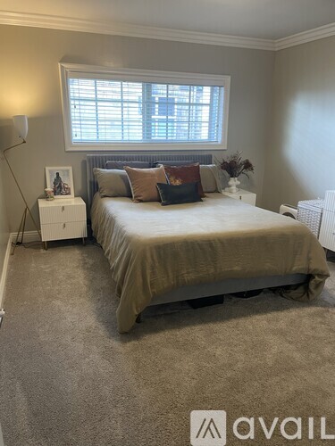 A bedroom with a bed, nightstand, and window.