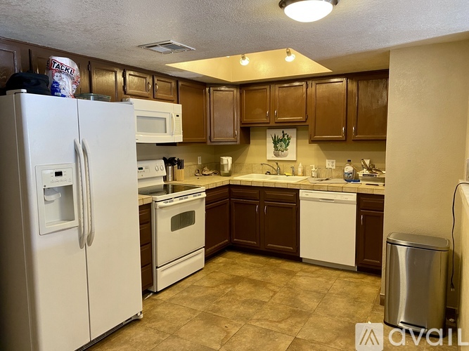 A kitchen with brown cabinets and white appliances.