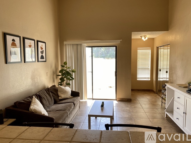 A living room with a couch, a coffee table, and a potted plant.
