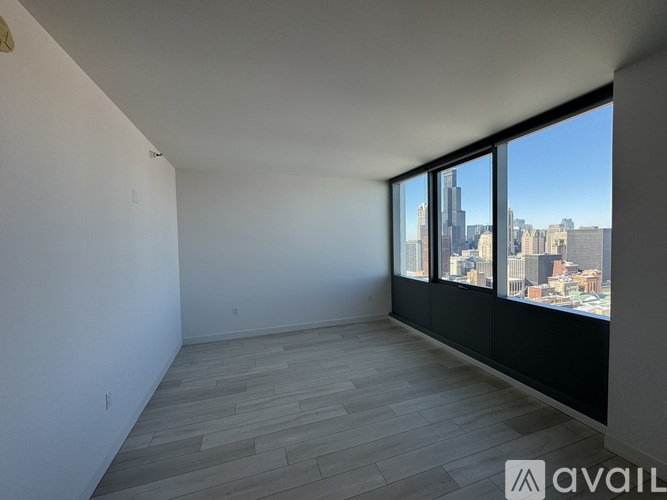 A spacious room with a view of the cityscape through large windows.