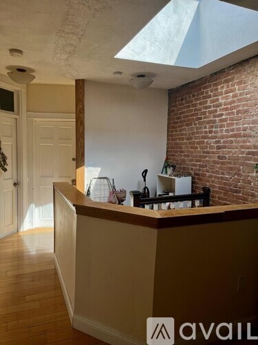 A kitchen with a brick wall and a wooden floor.