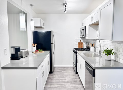 A kitchen with white cabinets and a black refrigerator.