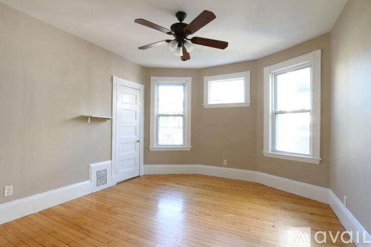 A room with a ceiling fan and three windows.
