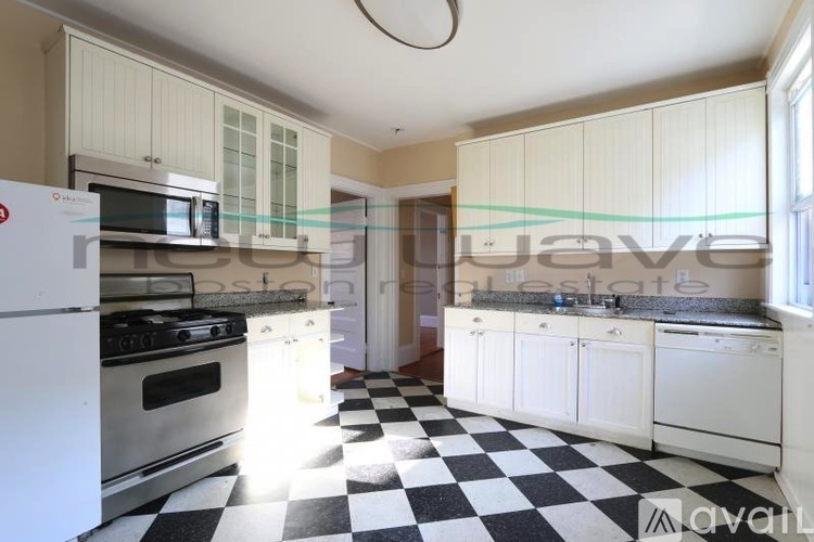 A kitchen with white appliances and checkered floor tiles.
