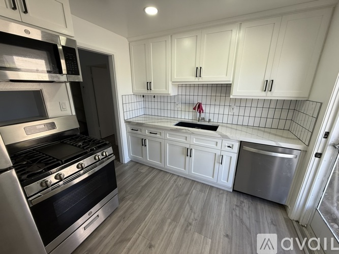 A kitchen with white cabinets and a black stove top oven.