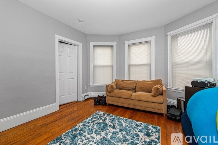 A living room with a couch, a rug, and a speaker.
