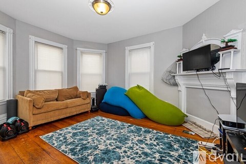 A living room with a couch, a rug, and a television on a stand.