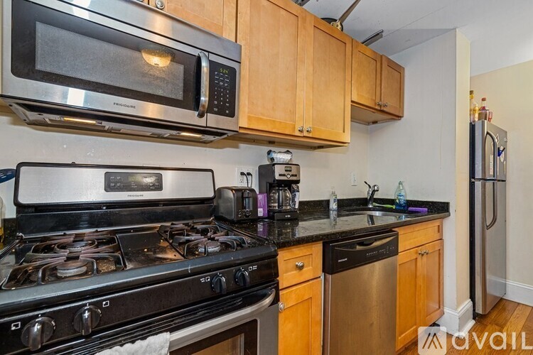 A kitchen with a black stove top oven and a silver microwave above it.