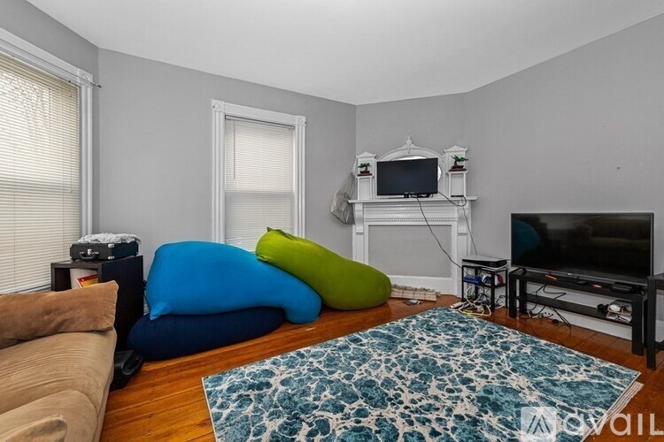 A living room with a brown sofa, a blue and a green bean bag chair, a television, and a fireplace.