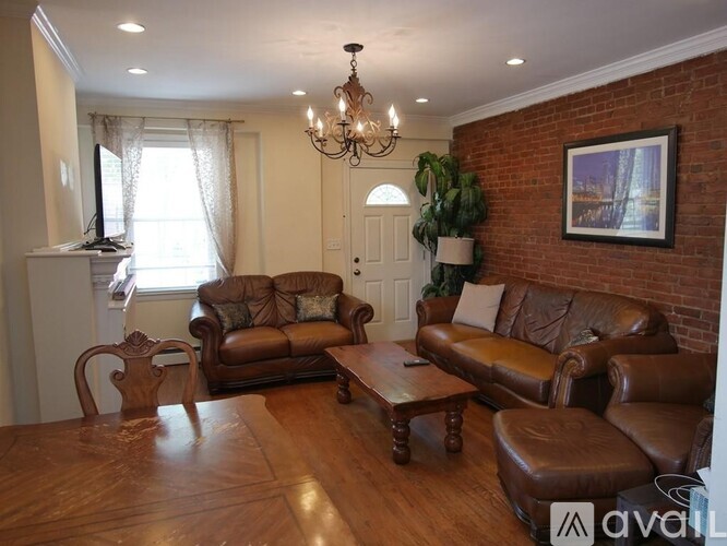 A living room with brown leather furniture and a chandelier.