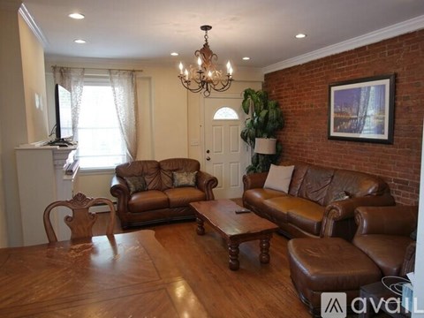 A living room with brown leather furniture and a chandelier.