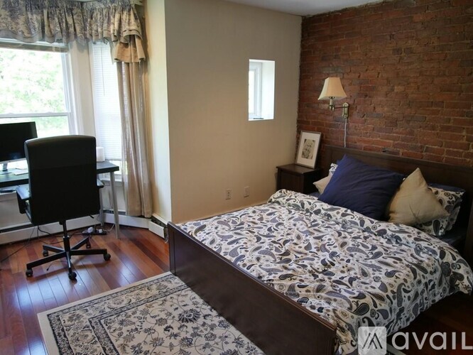 A bedroom with a brick wall and a bed with a floral patterned bedspread.