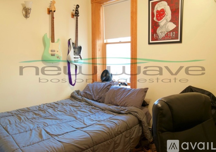 A bedroom with a bed, a chair, and guitars hanging on the wall.